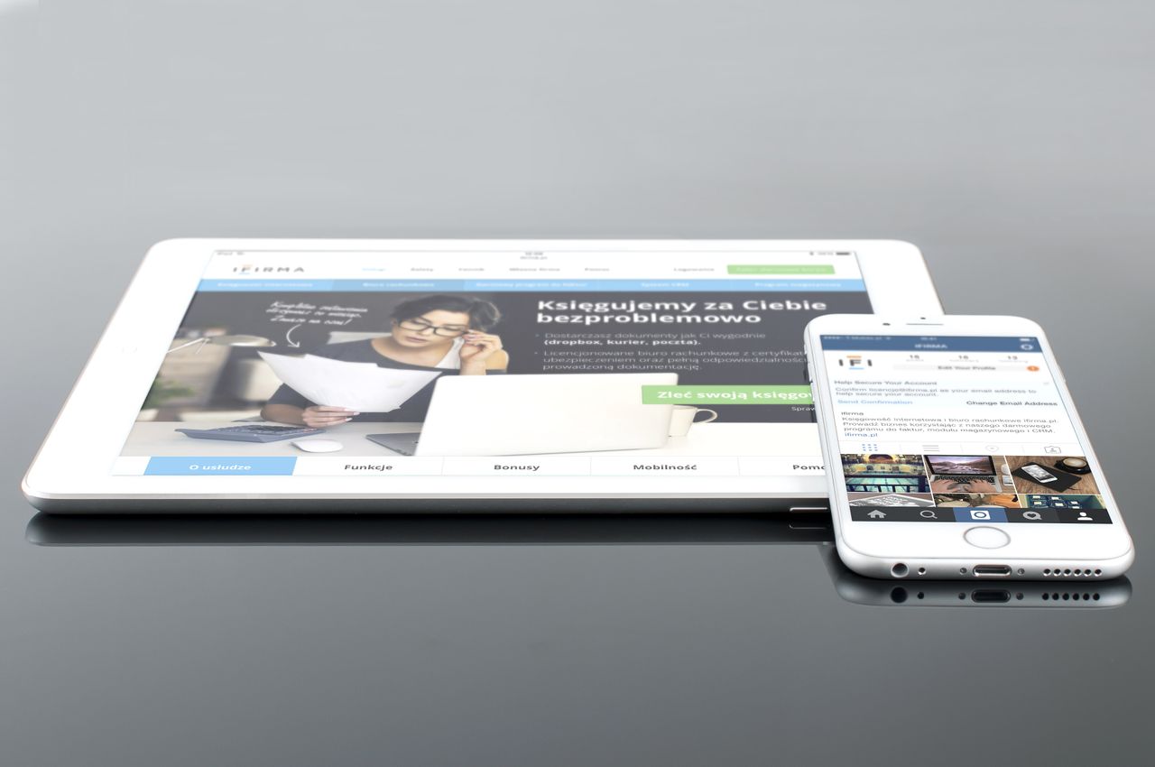 Tablette moderne et smartphone affichant du contenu web sur une surface réfléchissante, mettant en valeur la technologie et la connectivité.